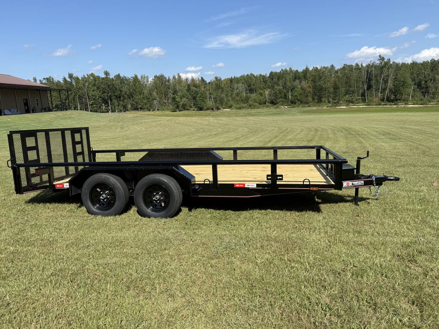 Side profile of a black Triple R tandem axle utility trailer with treated wood deck