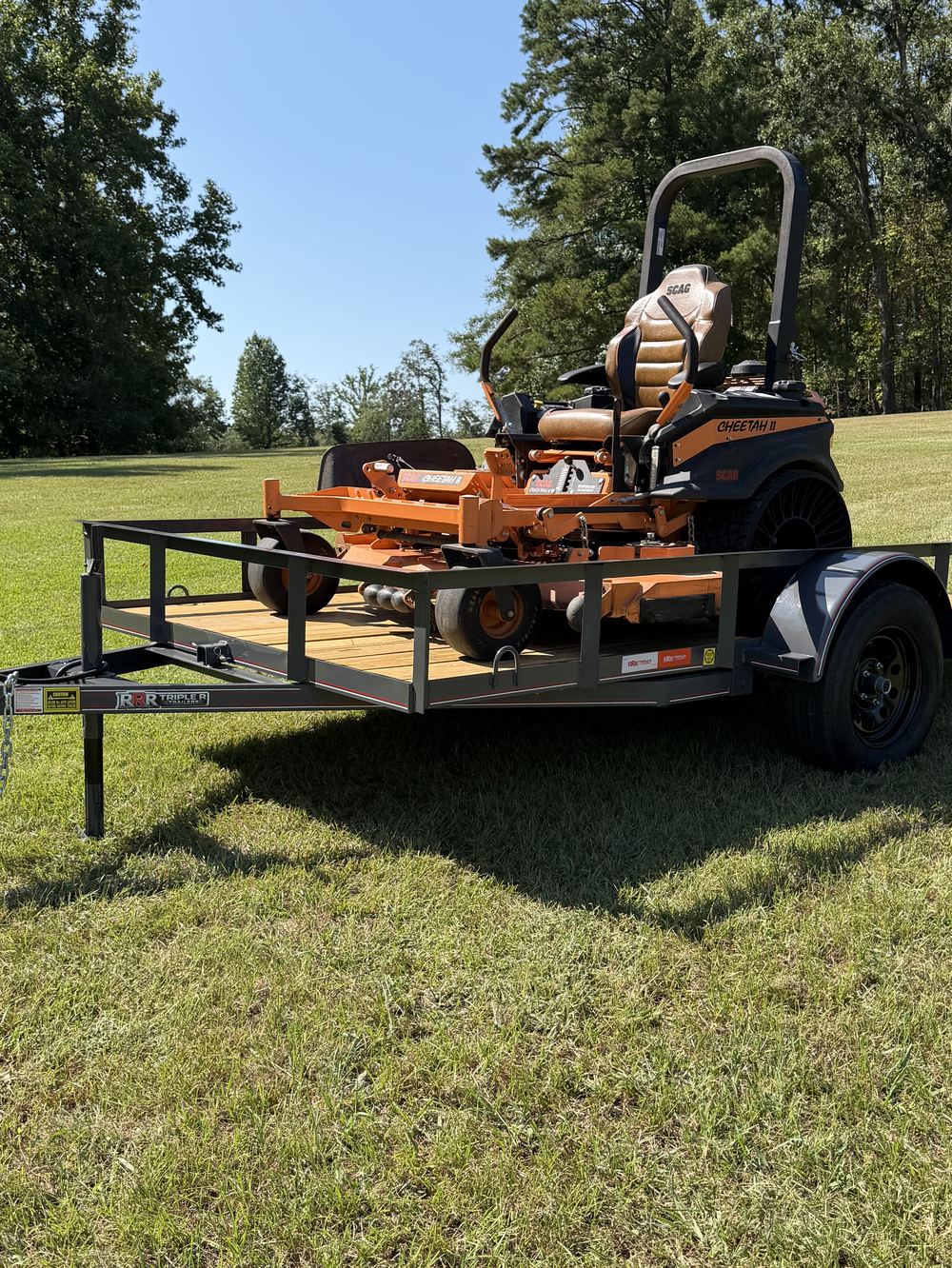 Orange Scag zero turn mower loaded on a black Triple R utility trailer