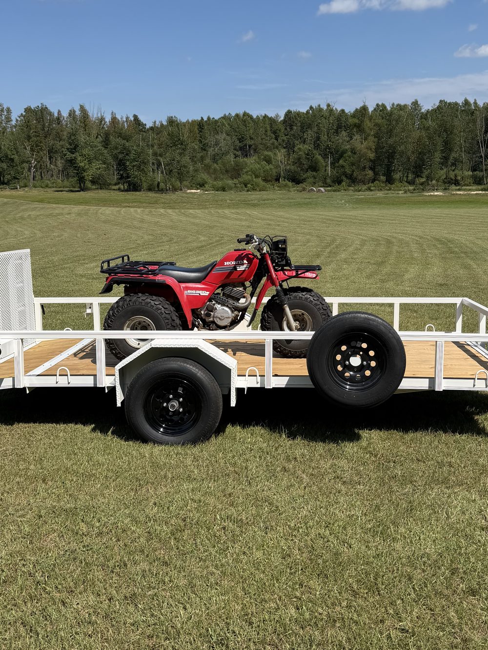 Red Honda ATV loaded on a white Triple R utility trailer